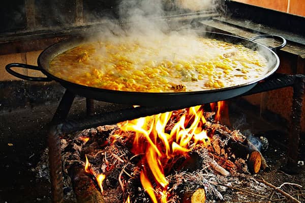 Paella przyrządzana na ogniu z drewna w czasie procesu gotowania.